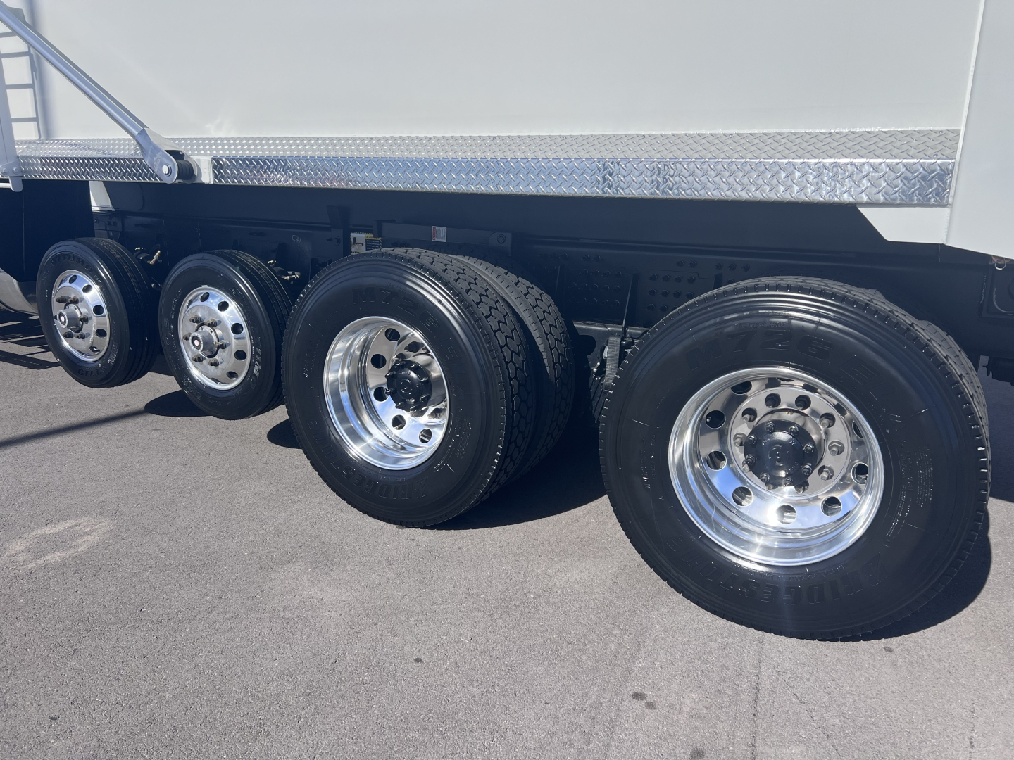 Mack GR64F dump truck rear wheels and tandem axle with polished chrome rims and dual rear tires.