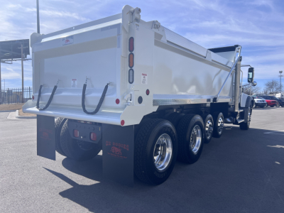 Dump truck rear and side view showing three axles and white Mack GR64F dump bed with tailgate, chrome wheels, and mud flaps.