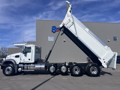 Mack GR64F dump truck in serviceable condition with hydraulic dump body raised, multiple axles and white cab.