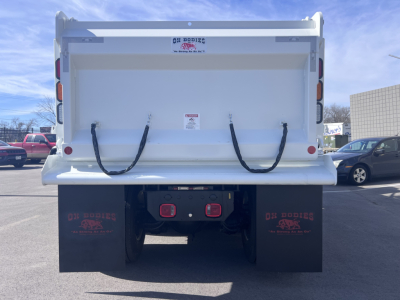 Rear view of a white Mack GR64F dump truck showing two black rear hoses, taillights, mud flaps with ‘D!Z BODiES’ branding, and a white dump bed.