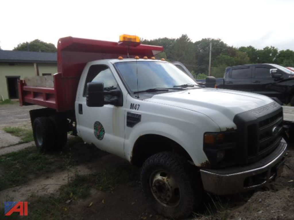 Ford F-350 Super Duty dump truck with plow body, white cab, orange beacon, black grille, dump bed with red sides, front dual wheels, M47 decal on fender