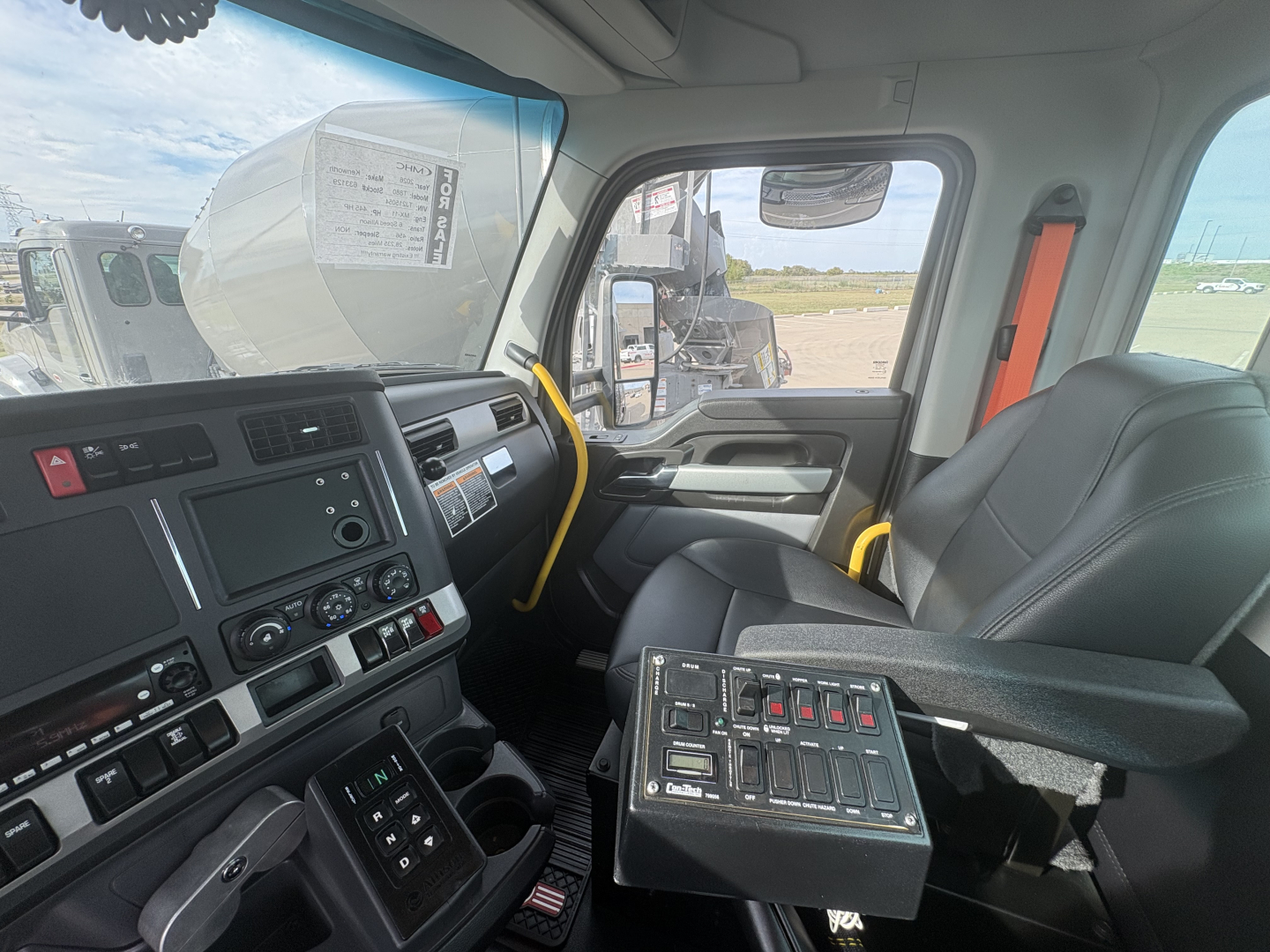 Truck cab interior of a Kenworth T880 with dashboard controls, steering wheel, and a tech panel with multiple switches in the center. Visible text on dashboard and controls includes various knobs and labels, but no legible serials or part n
