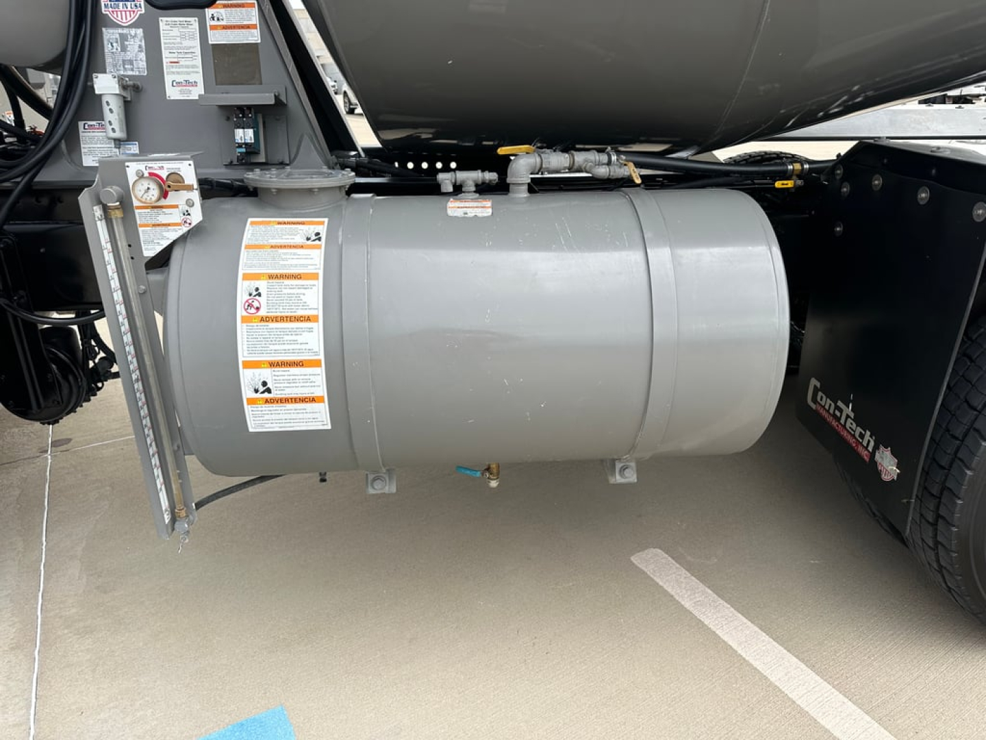 Kenworth T880 mixer truck fuel tank/air tank assembly with warning labels and mounting brackets visible under the chassis