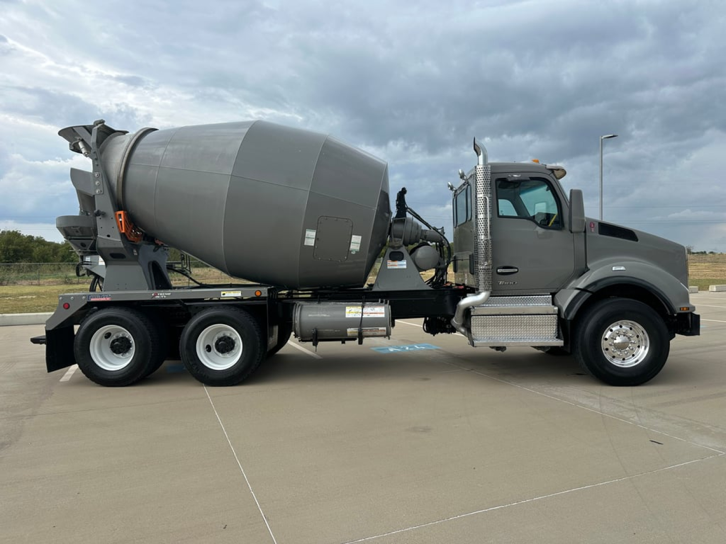 Kenworth T880 mixer truck side view showing large concrete mixer drum and cab with chrome steps and side mirror