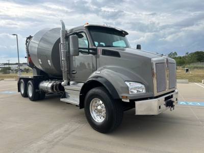 Kenworth T880 mixer truck in gray with concrete mixer, front view angled show chrome bumper, large grille, side exhaust, and dual rear axles.