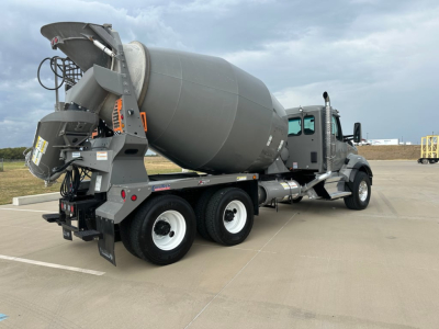 Kenworth T880 mixer truck in a parking lot, rear concrete mixer drum and chute visible, side view showing wheels and cab.
