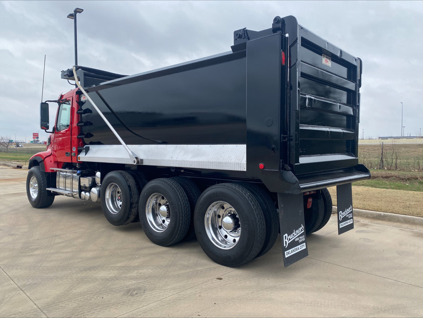 Volvo VHD84F200 dump truck body on red cab with black dumping container and dual rear axles visible.