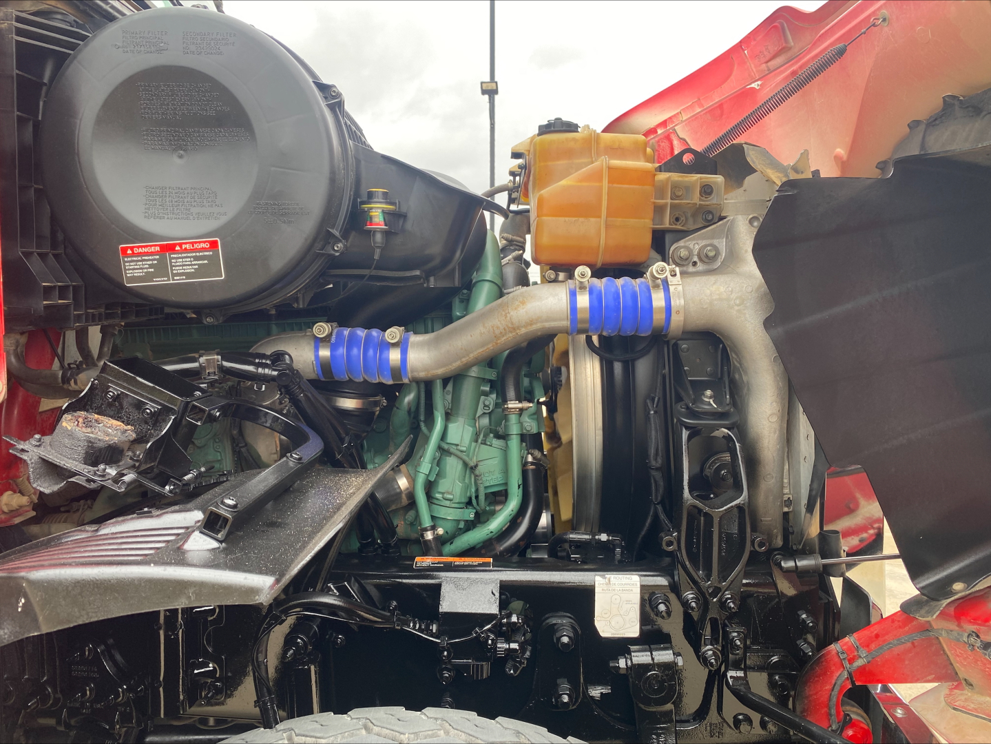Volvo VHD84F200 truck engine bay showing intake, hoses, coolant reservoir, and engine components.