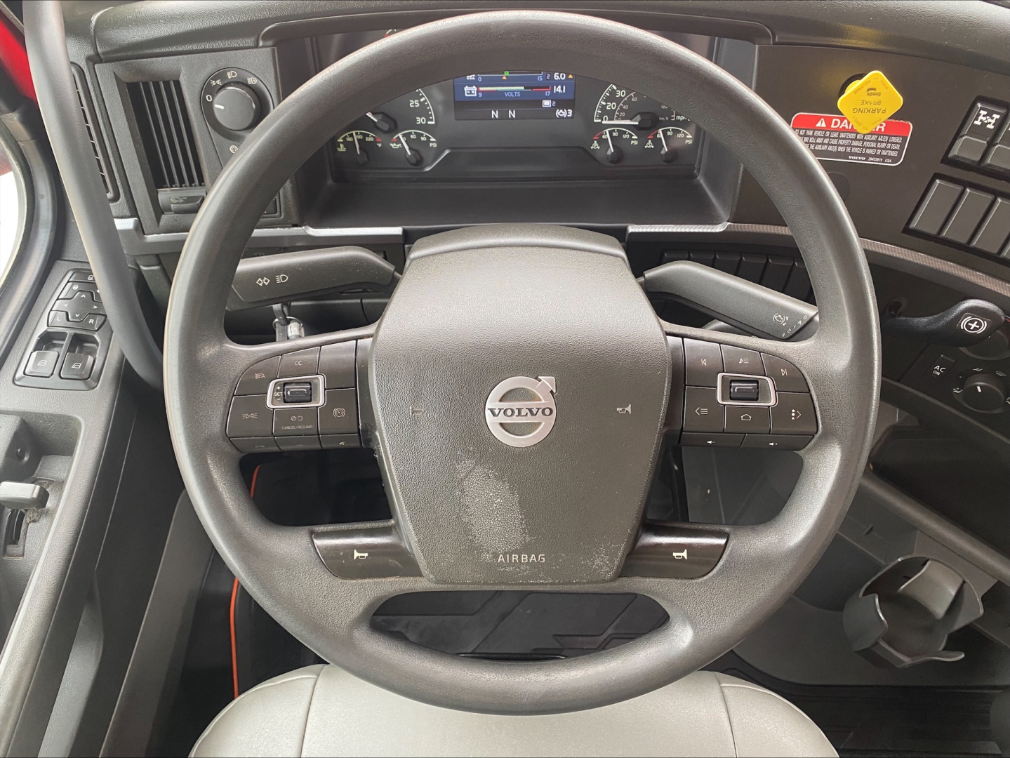 Volvo steering wheel and dashboard inside cab showing Volvo logo on steering wheel and instrument cluster.