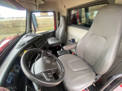Cab interior of a Volvo truck with steering wheel, driver seat and passenger seat; dashboard with gauges and controls visible.