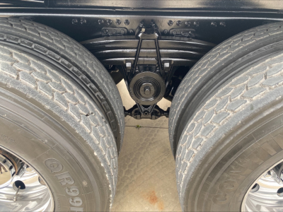 View under a Volvo VHD84F200 dump truck showing dual rear axles, leaf springs, and differential/axle housing. Visible tires and suspension components.