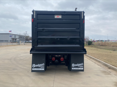 Dump truck bed rear view showing black cargo box and dual rear fender mud flaps with Bruckner’s logos and Oklahoma City text