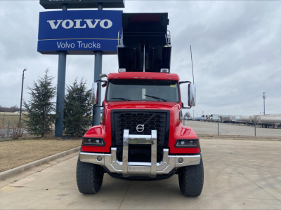 Front view of a red Volvo VHD truck in a dealership lot with a Volvo sign in the background.
