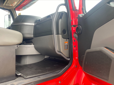 Cab interior of a red Volvo truck showing entry area, dashboard, steering area, and door panel.
