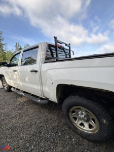 Chevrolet Silverado 1500 crew cab pickup truck side/back view showing white paint, crew cab, rear bed, ladder rack, and running boards.