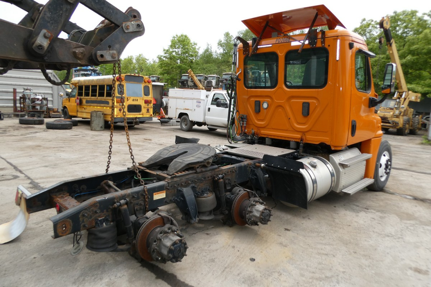 Freightliner Cascadia 125 cab in orange with exposed chassis and drivetrain components, rear view shows axles and suspension.