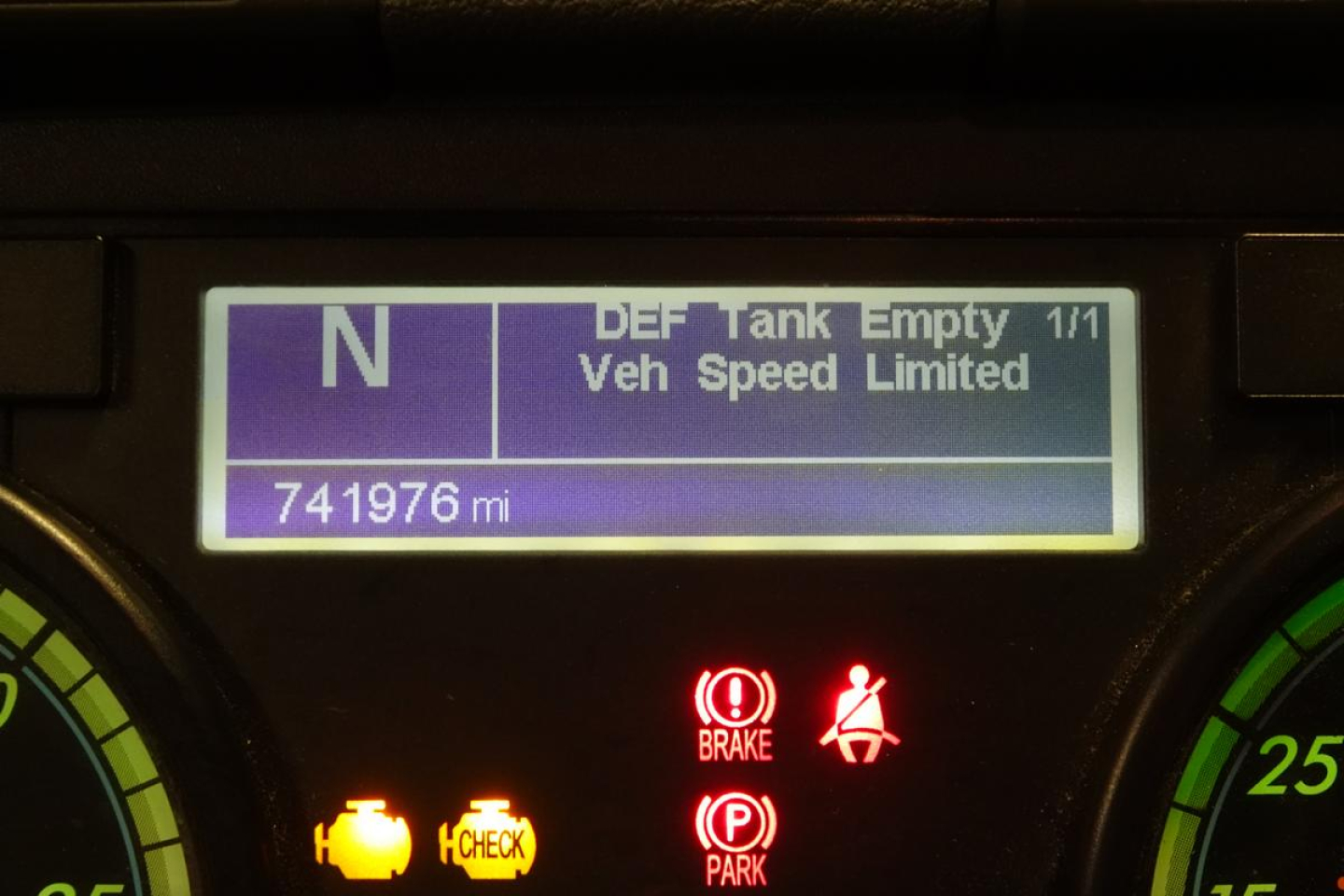 Truck dashboard display showing vehicle speed limited, mileage 741976 mi, warning lights including brake and parking, DEF tank empty indicator.