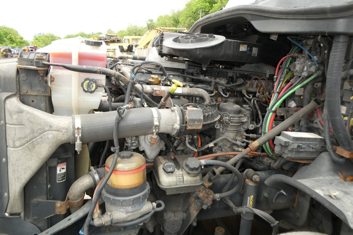 Cascadia 125 engine bay showing coolant reservoir, air intake, hoses, wiring harness, and diesel engine components.