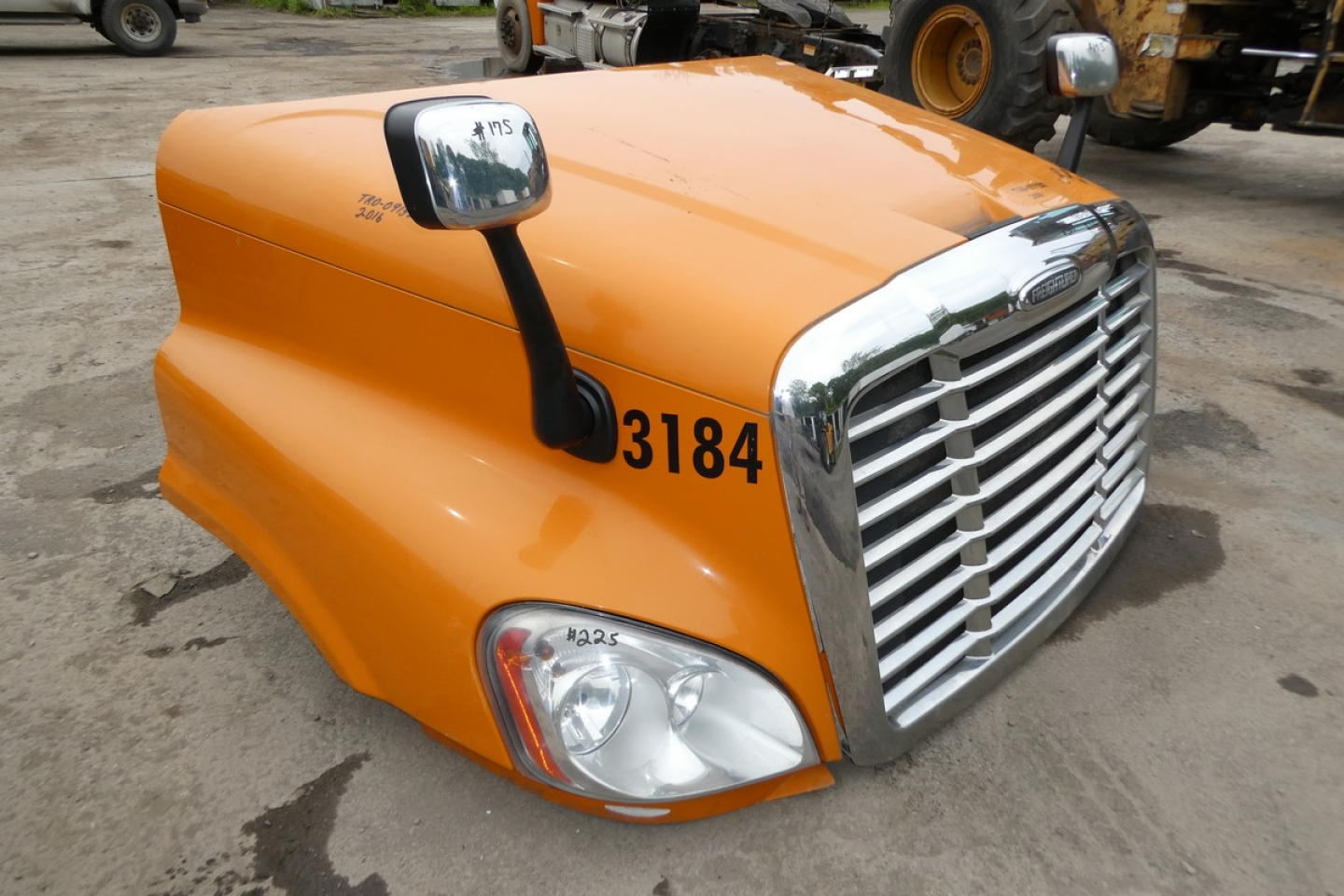 Orange Freightliner Cascadia 125 truck hood with large chrome grille and headlight, side mirror, and number 3184.
