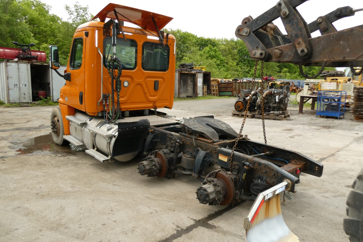Orange Freightliner Cascadia 125 cab with removed tractor frame and components in yard. VIN and stock not visible on image.