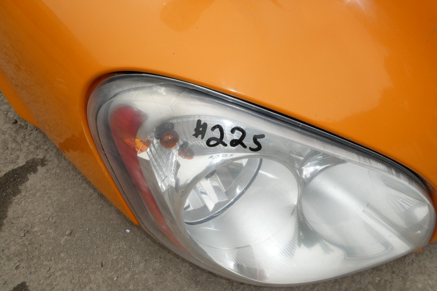 Headlight assembly of a Freightliner Cascadia headlight with '#225' marking on the lens.