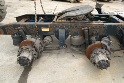 Freightliner Cascadia 125 chassis rear view showing hub assemblies and brake components with rust and debris, undercarriage with chain and fuel tank cap visible.