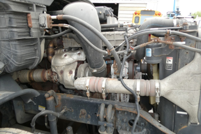 Engine bay showing coolant hoses, turbocharger, and intercooler piping in a Freightliner Cascadia cab over-engine area.
