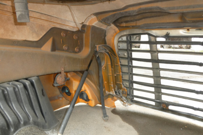 Truck front lower cab area of a 2017 Freightliner Cascadia 125 showing damaged bumper and grille with exposed frame and hood hinge.