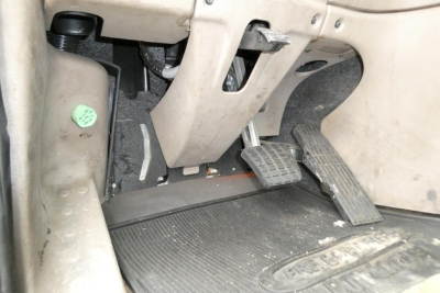 Dashboard area showing accelerator and brake pedals inside Freightliner Cascadia 125 cab; floor mat and pedal assembly visible.