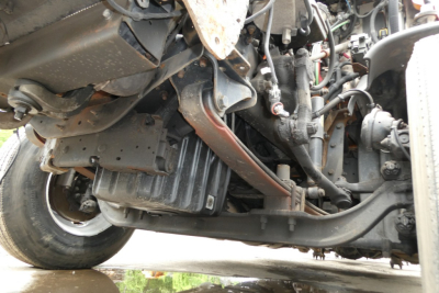 Underbelly of a Freightliner Cascadia 125 showing engine components, wiring, and frame with visible metal brackets and hoses.