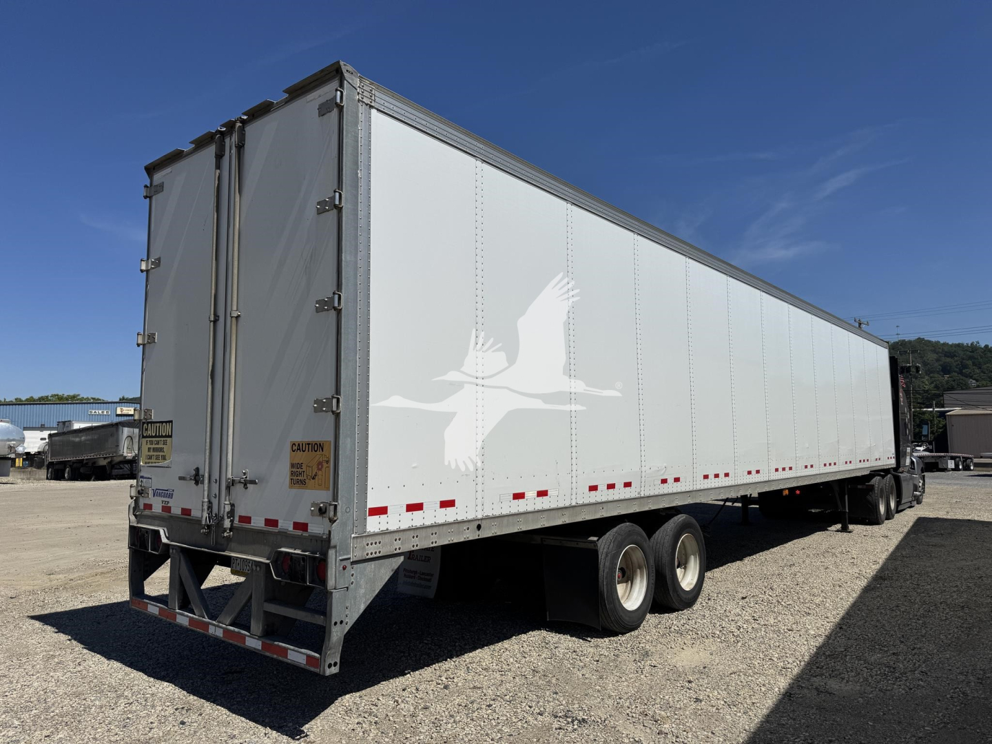 Trailer side view showing large white silhouette graphic on trailer wall and rear doors, Vanguard VXP trailer with dual rear axles.