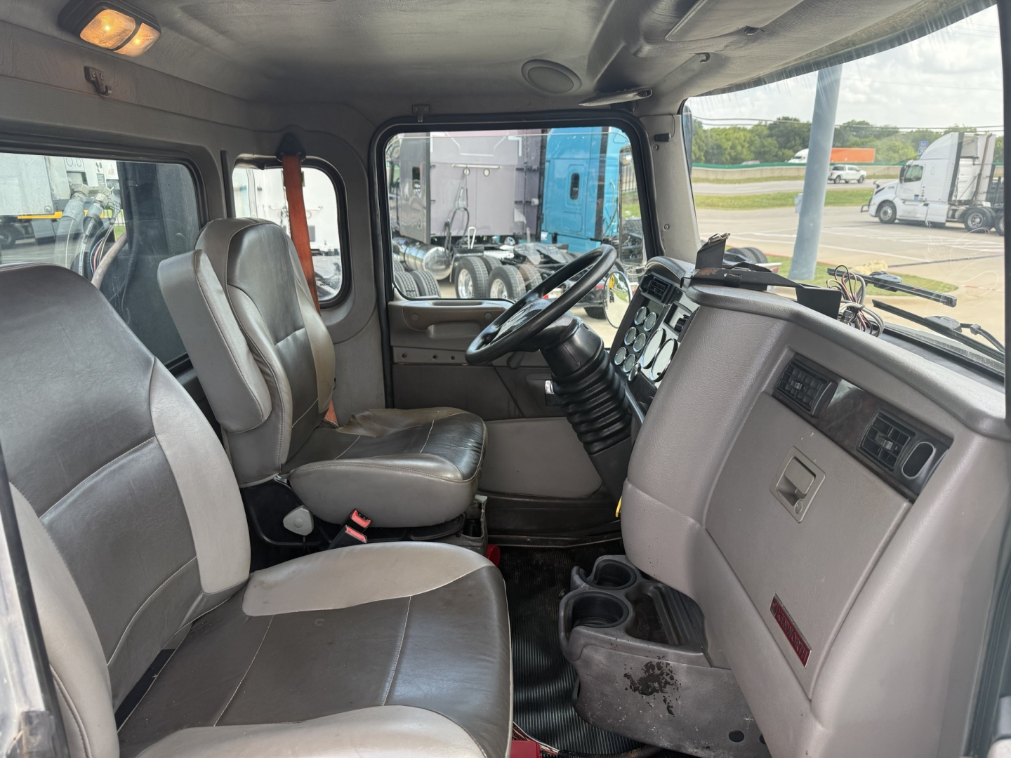 Kenworth T270 cab interior showing driver and passenger seats, dashboard, steering wheel, and center console with cup holders.