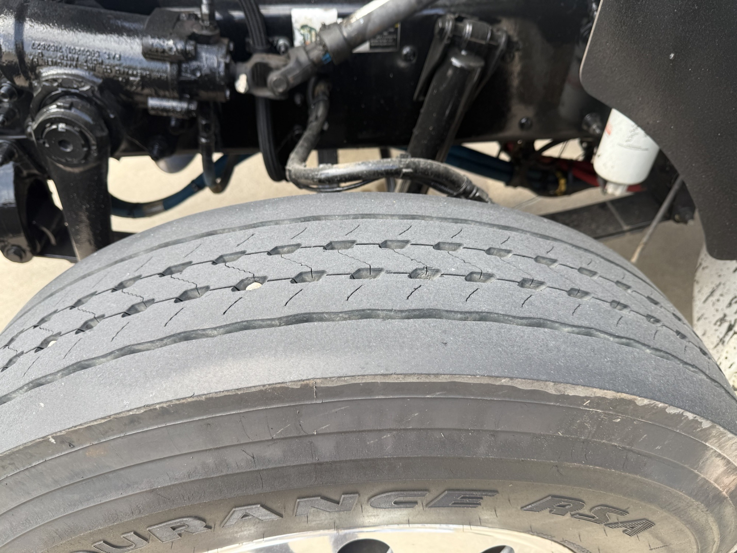 Kenworth truck front wheel area showing tire tread and suspension components with VIN/stock info overlay not visible.