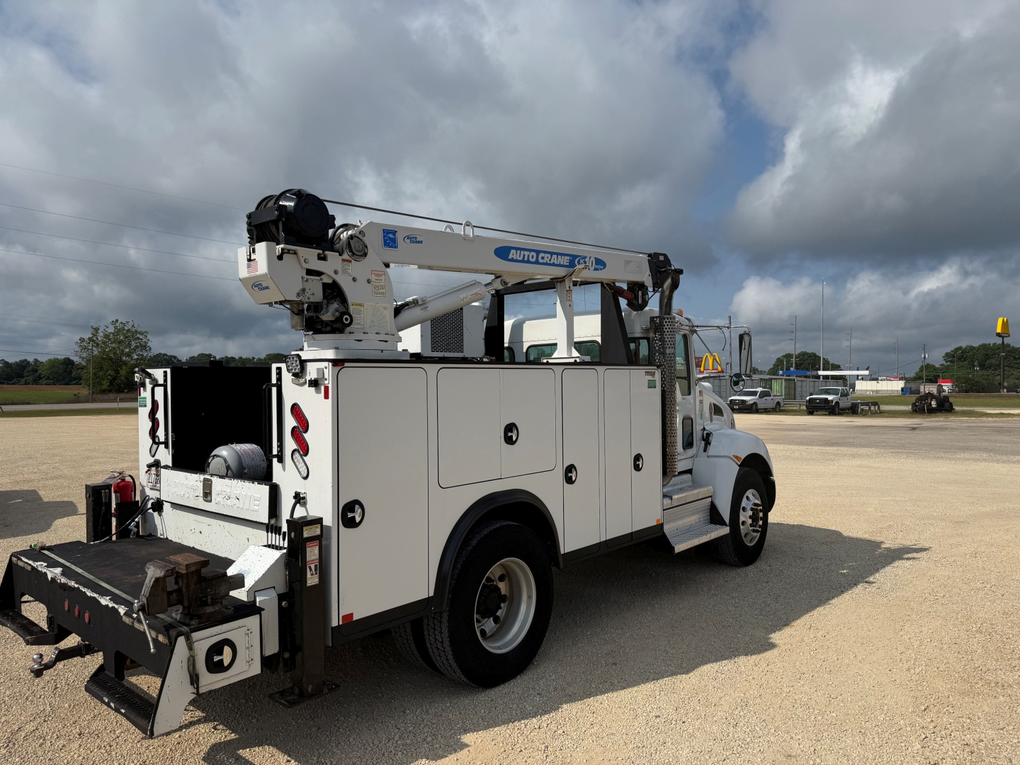 Kenworth T270 service truck in a yard with mounted crane, utility compartments, and rear work equipment. Side view shows crane boom and storage compartments.