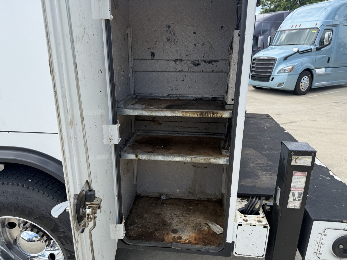 Kenworth T270 service truck interior with two metal shelves and rust stains in the cargo compartment.