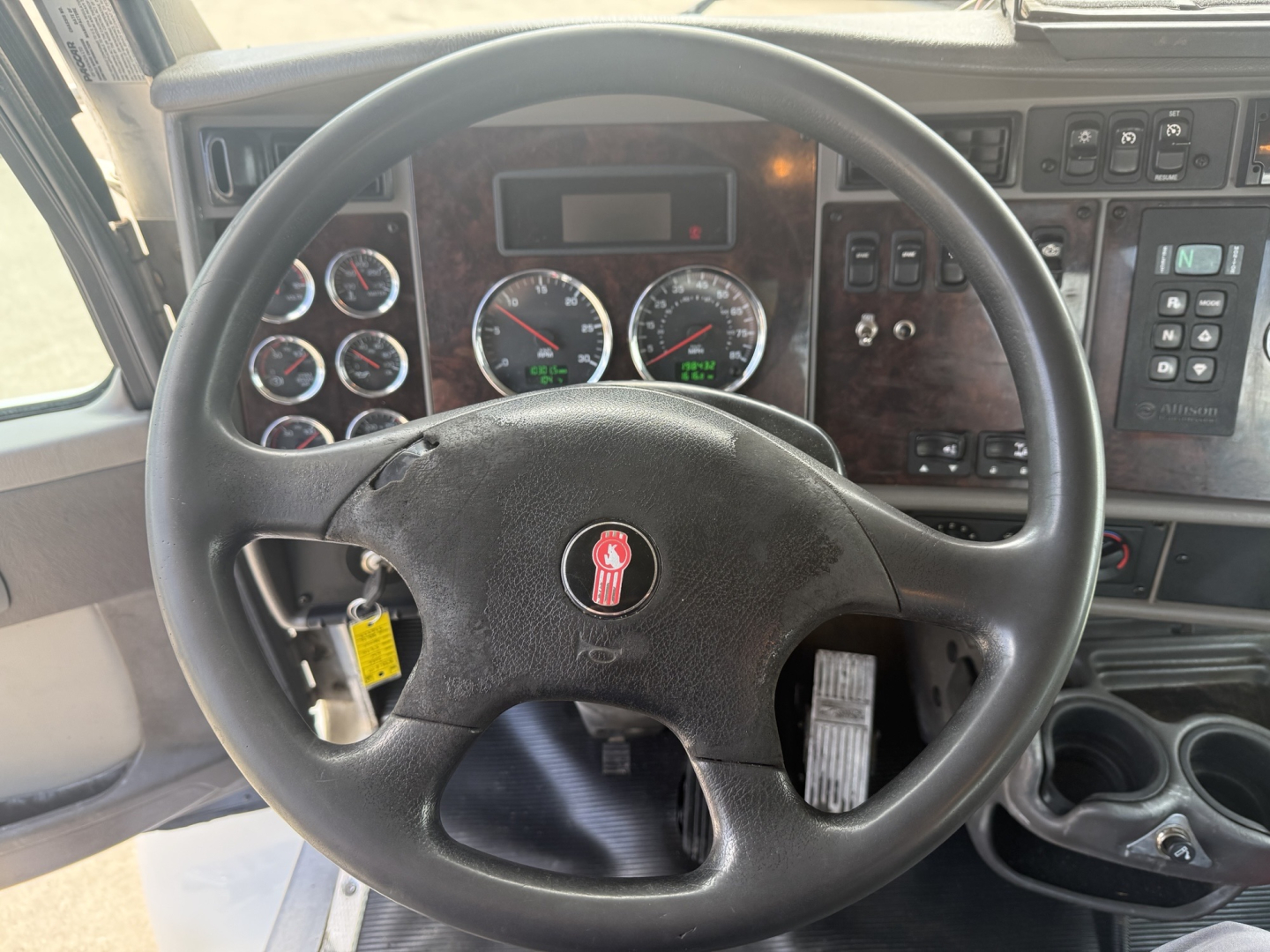 Kenworth T270 cab interior showing steering wheel, dashboard gauges, and control panels with multiple switches.