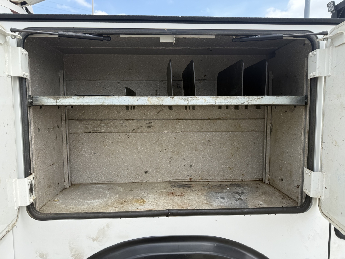 Truck bed/storage area of a 2020 Kenworth T270 with empty metal cargo box visible from rear opening.