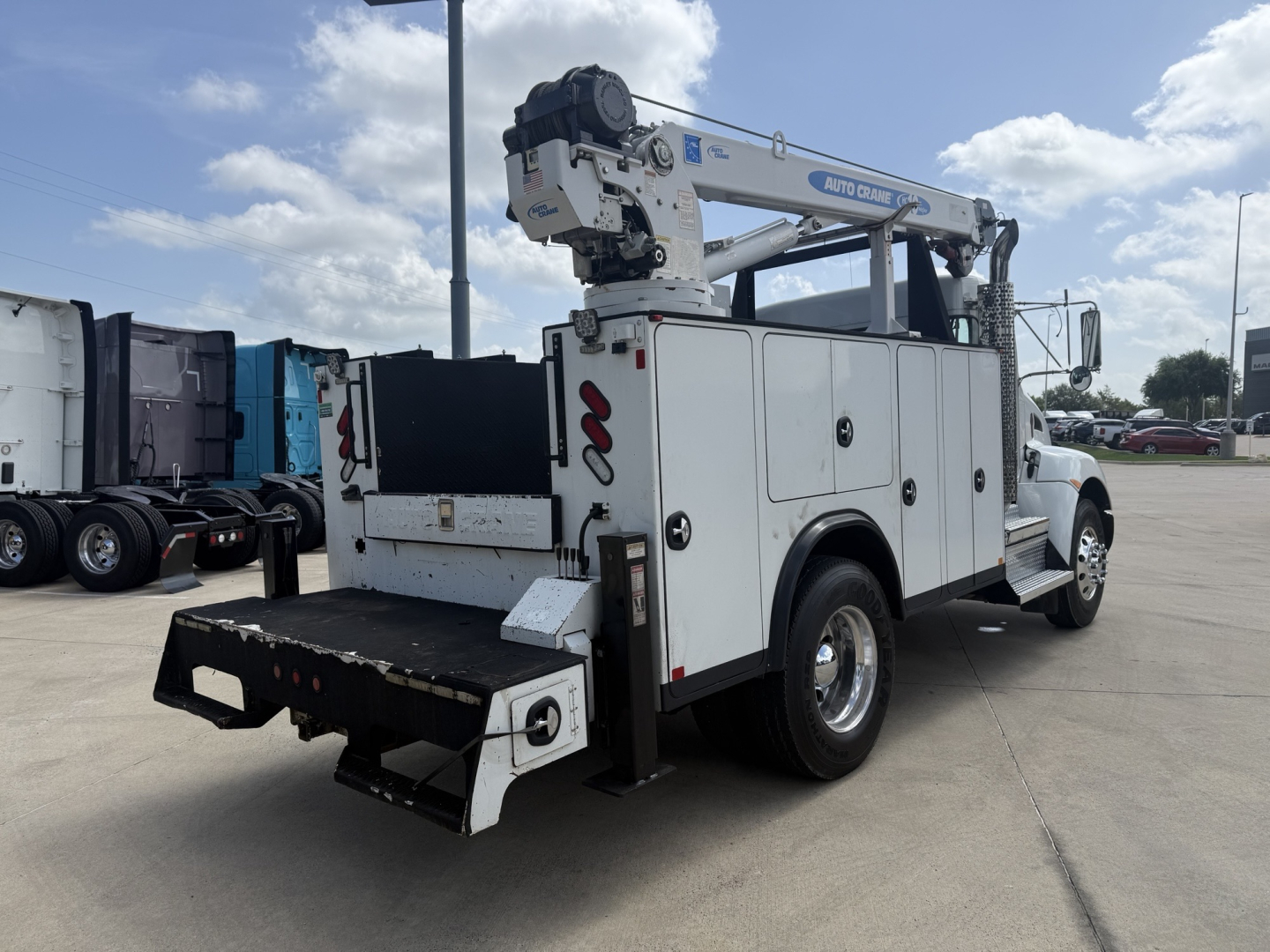 Kenworth T270 utility/service truck with crane rack and storage compartments, side-view showing rear hoist and tool storage, white paint, no visible damage.