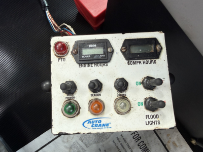 Engine control panel on a Kenworth service truck showing gauges and switches: hours, 6 compartment hours, engine hours, various indicator lights, and Auto Crane logo.