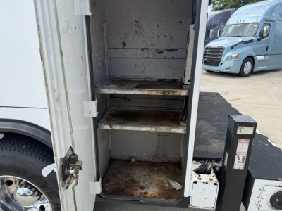 Kenworth T270 service truck interior with two metal shelves and rust stains in the cargo compartment.