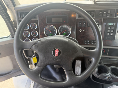 Kenworth T270 cab interior showing steering wheel, dashboard gauges, and control panels with multiple switches.