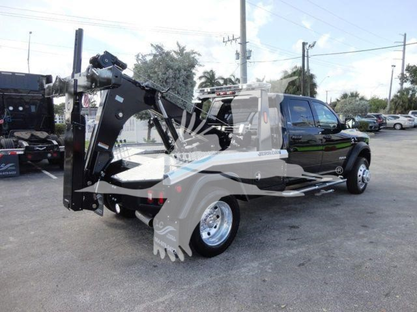 Ram 5500 SLT tow truck with industrial winch attachment mounted on wheel-lift, side view showing heavy-duty hydraulic apparatus and platform truck bed.