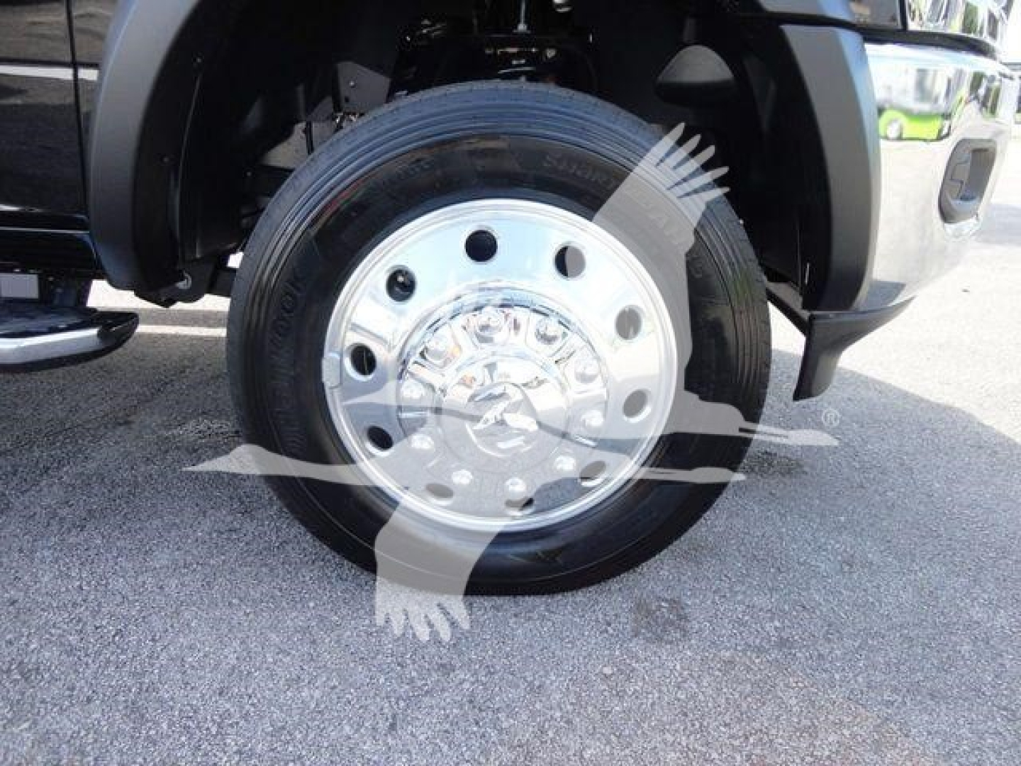 Truck wheel: chrome steel rim with black tire, front wheel well visible on a Ram 5500 SLT chassis cab.