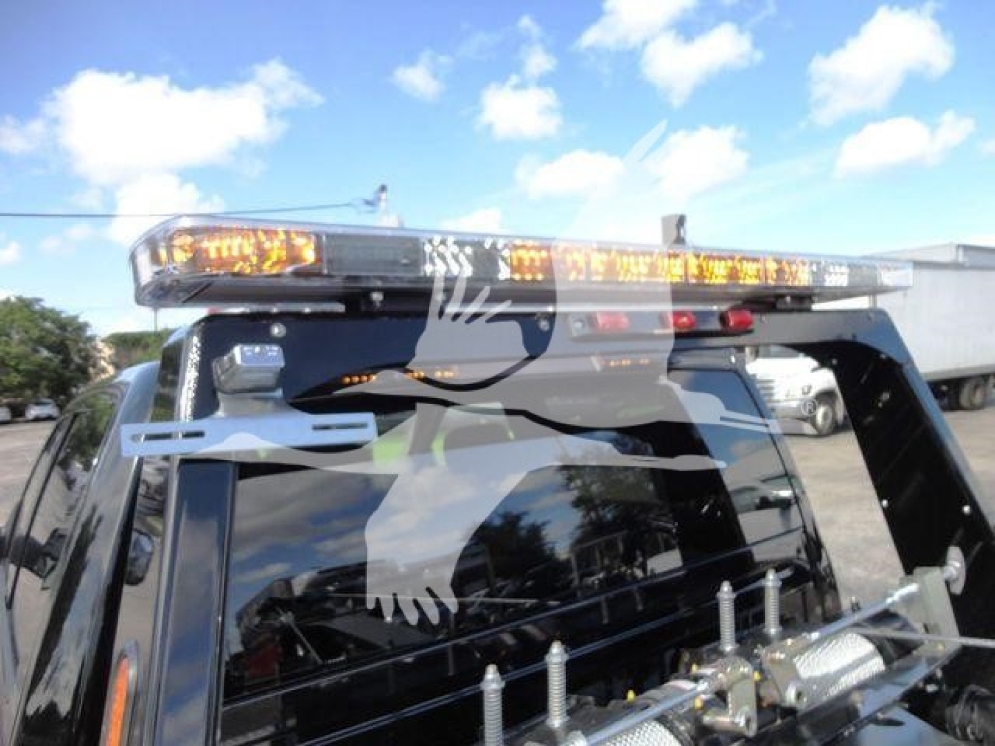 Ram 5500 truck with light bar and winch indication. View shows roof-mounted amber beacon lights and partial reflection on window glass.