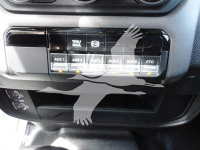 Dashboard auxiliary switches labeled AUX 1 to AUX 6 and PTO in a Ram 5500 interior panel showing Tow/Haul switch and blank storage below.