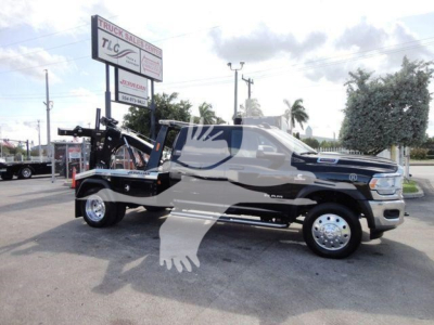 Ram 5500 pickup truck with winch assembly on a trailer hitch setup, side view showing SLT trim, black and gray color scheme, large tow rig with chrome wheels.