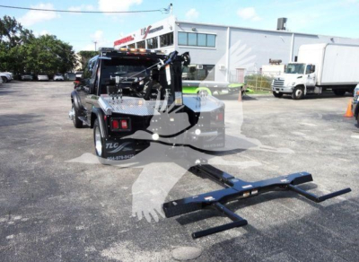 Ram 5500 SLT pickup with a front-mounted winch and tow hitch, black exterior, concrete lot, industrial building in background.