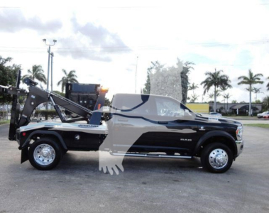 Ram 5500 SLT pickup with winch equipment and crane arm on the bed, side view showing wheel wells and chrome accents.