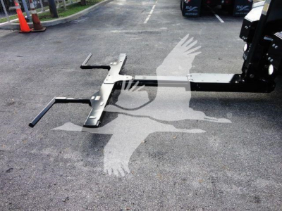 Winch mount assembly on a Ram 5500 truck, industrial metal frame with black handles and brackets, resting on asphalt.