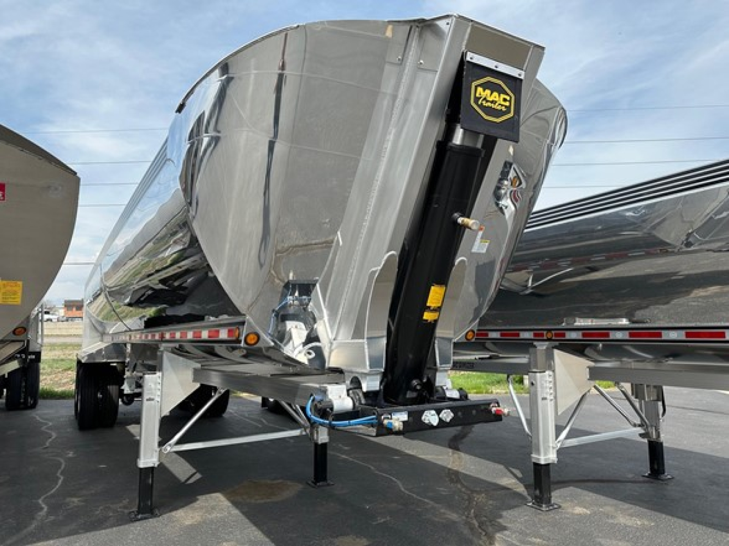 Dump trailer with Mac Macsimiser logo, polished aluminum tank, front hitch and support legs visible.